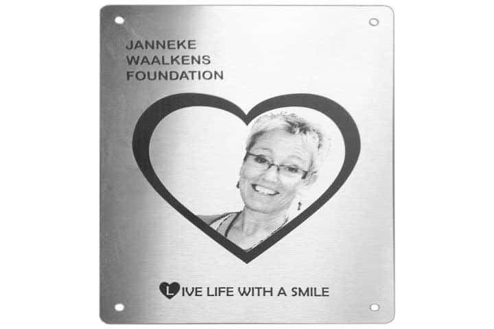 Gedenkbord van RVS ter nagedachtenis van Janneke Waalkens. Te zien is een foto in een hart met tekst daaromheen via lasergravure aangebracht