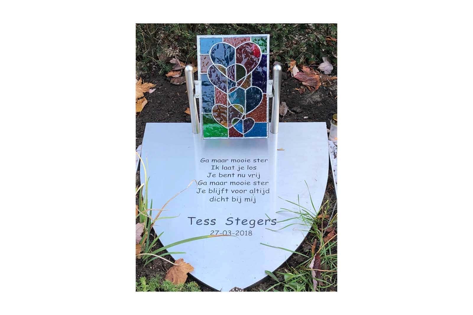 gepersonaliseerd grafmonument van RVS met gefreesde tekst die ingelakt is. Met daarop een glas in lood raampje