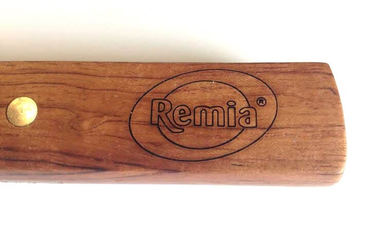 Een close up van een houten handvat met het logo van Remia erin gegrafeerd
