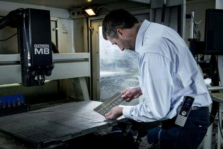 Medewerker Edwin van Gravure85 controleert een metalen plaatje dit door de Datronmachine is gegraveerd