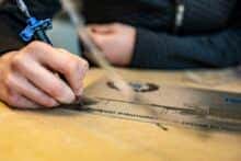 Close up van een hand die een metalen plaat aan het inlakken is