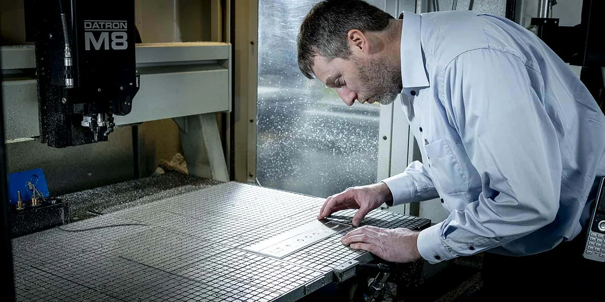 Medewerker Gravure85 graveert een metalen plaatjes op de Datronmachine